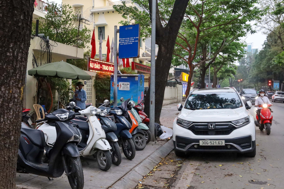 Vỉa hè làm nơi trông xe máy, dưới đường ôtô đỗ chắn khiến hành khách không có chỗ đứng chờ. (Ảnh: Nguyễn Kế Tùng/TTXVN phát)