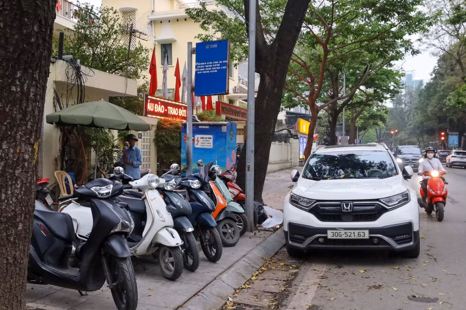 Vỉa hè làm nơi trông xe máy, dưới đường ôtô đỗ chắn khiến hành khách không có chỗ đứng chờ. (Ảnh: Nguyễn Kế Tùng/TTXVN phát)