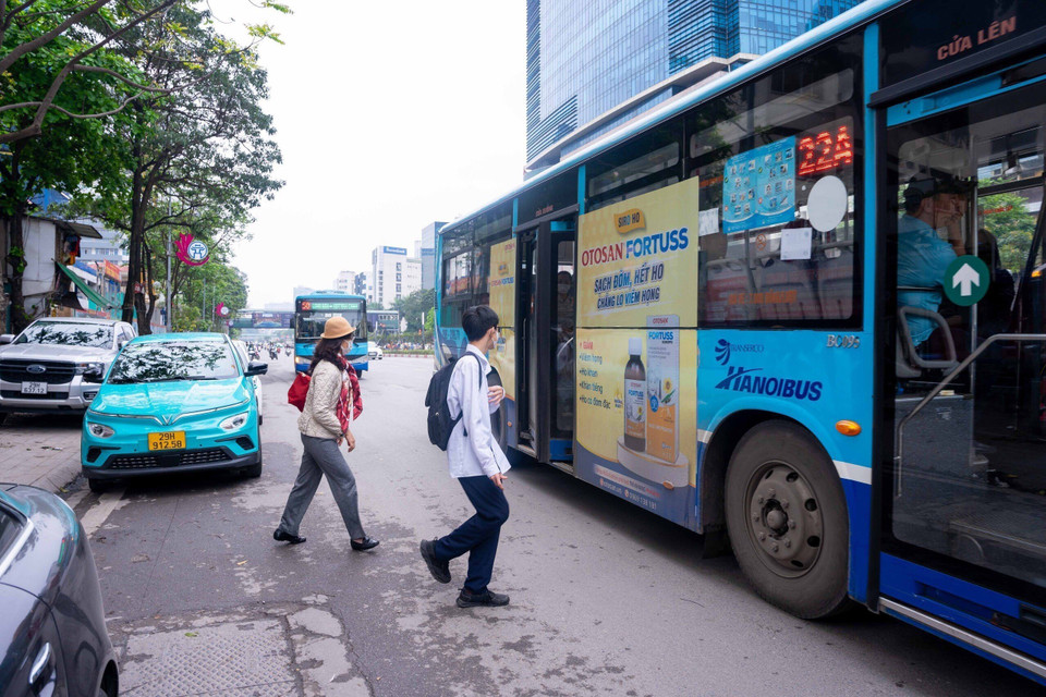 Hành khách phải đi ra lòng đường mới lên được xe buýt do xe không vào được điểm dừng vì vướng các phương tiện khác đỗ chắn. (Ảnh: Nguyễn Kế Tùng/TTXVN phát)