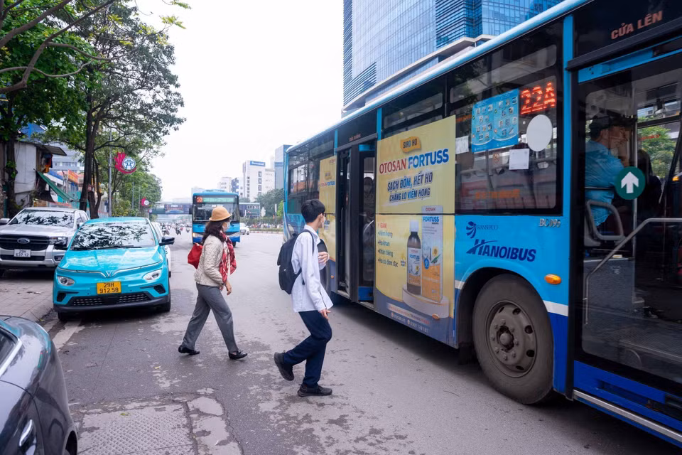 Hành khách phải đi ra lòng đường mới lên được xe buýt do xe không vào được điểm dừng vì vướng các phương tiện khác đỗ chắn. (Ảnh: Nguyễn Kế Tùng/TTXVN phát)