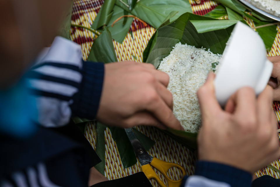 Học sinh trường THPT Nguyễn Trường Tộ tự tay tải nghiệm hoạt động gói bánh chưng và những phần quà nhỏ xinh để tặng những bạn học có hoàn cảnh khó khăn. (Ảnh: Bích Huệ/TTXVN)