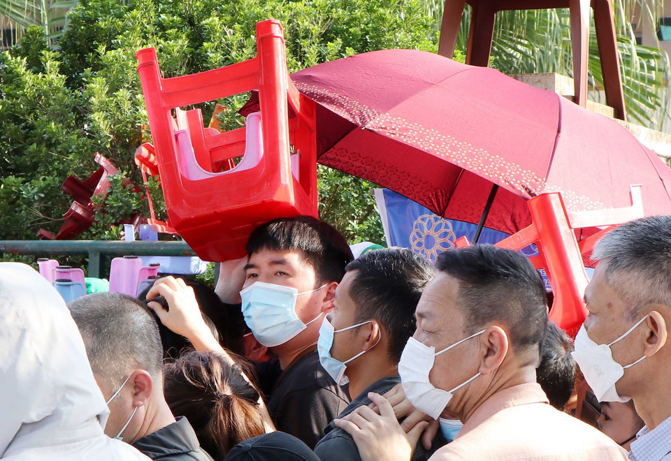 Một người xếp hàng mua vé dùng ghế để che nắng, chờ đến lượt được mua vé. (Ảnh: Trung Kiên/TTXVN)