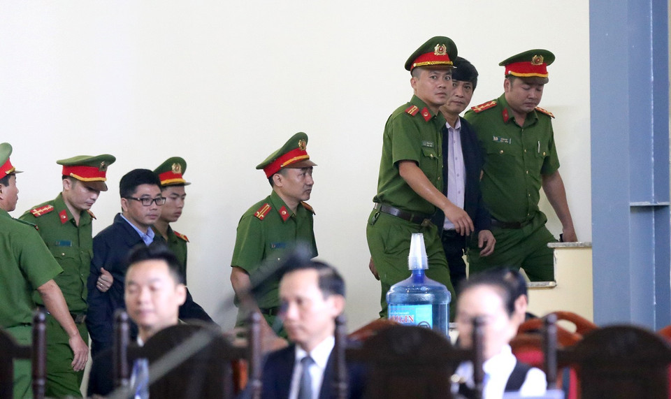 Bị cáo Nguyễn Thanh Hóa, nguyên Cục trưởng Cục Cảnh sát Phòng chống tội phạm sử dụng công nghệ cao (bên phải) và bị cáo Nguyễn Văn Dương (nguyên Chủ tịch Hội đồng thành viên Công ty Đầu tư phát triển an ninh công nghệ cao - CNC) được dẫn giải vào phòng chờ xét xử. (Ảnh: Trung Kiên/TTXVN)