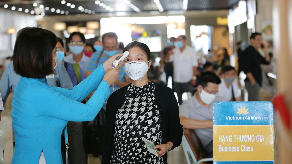 Nhân viên hãng hàng không đo thân nhiệt hành khách. (Ảnh: CTV/Vietnam+)
