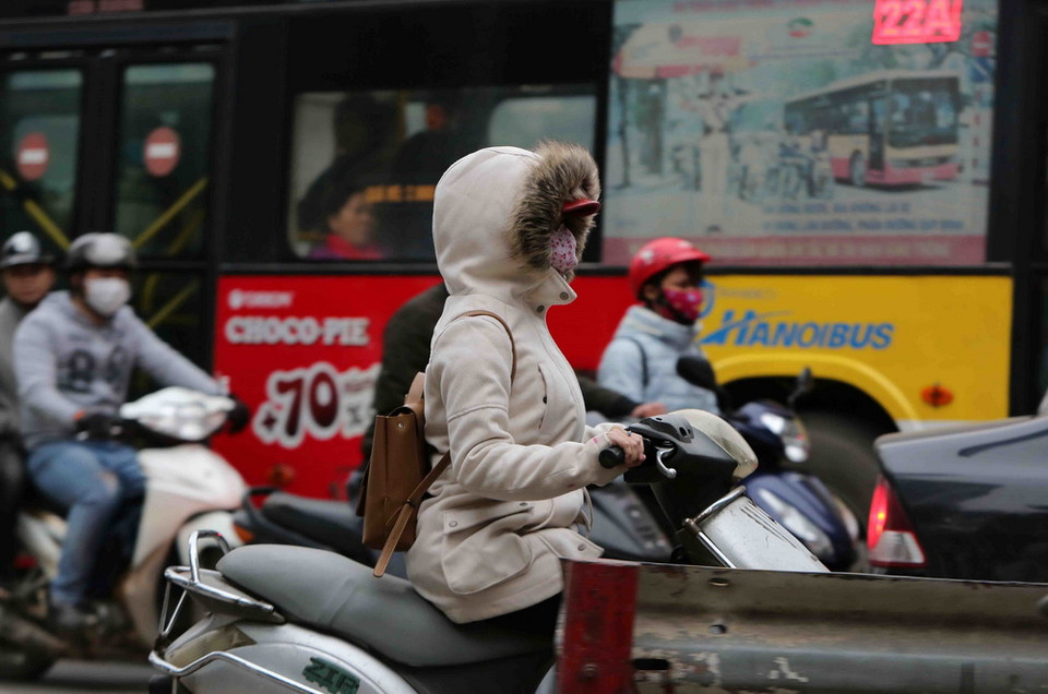 Người dân tham gia giao thông trong trang phục kín mít để tránh rét. (Ảnh: Thành Đạt/TTXVN)