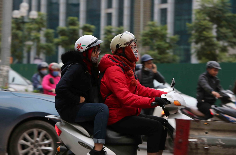 Người dân tham gia giao thông trong trang phục kín mít để tránh rét. (Ảnh: Thành Đạt/TTXVN)