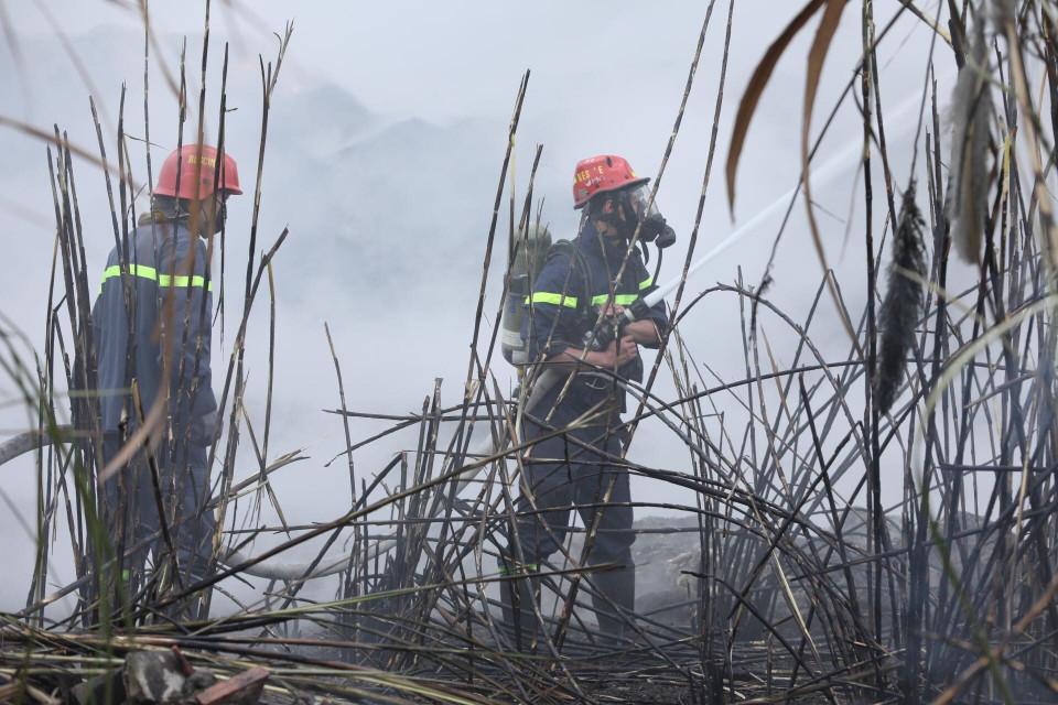 Các chiến sỹ phòng cháy chữa cháy tích cực khống chế ngọn lửa lây lan sang khu vực lân cận. (Ảnh: Thành Đạt/TTXVN)