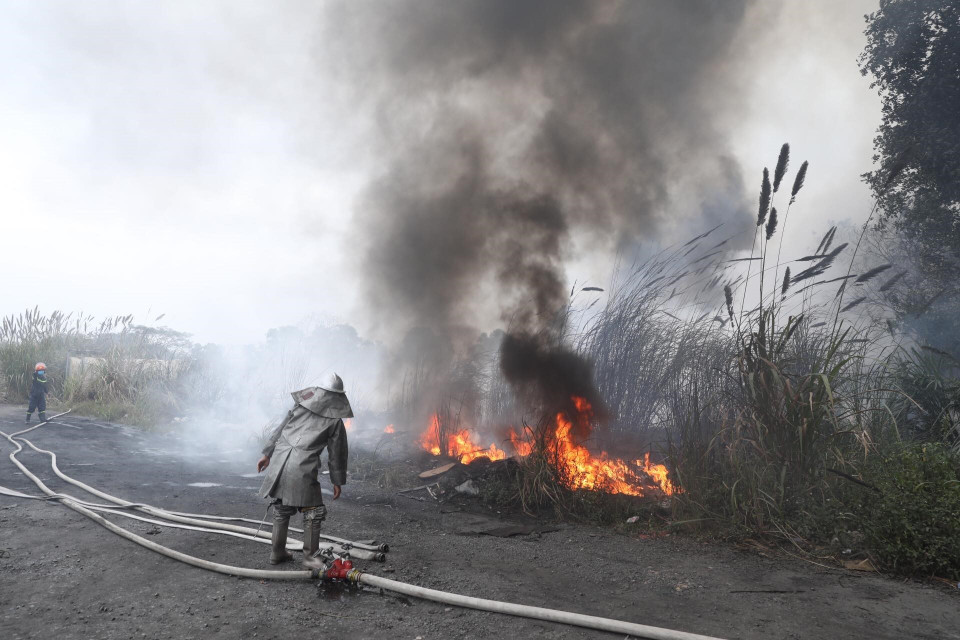 Các chiến sỹ phòng cháy chữa cháy tích cực khống chế ngọn lửa lây lan sang khu vực lân cận. (Ảnh: Thành Đạt/TTXVN)