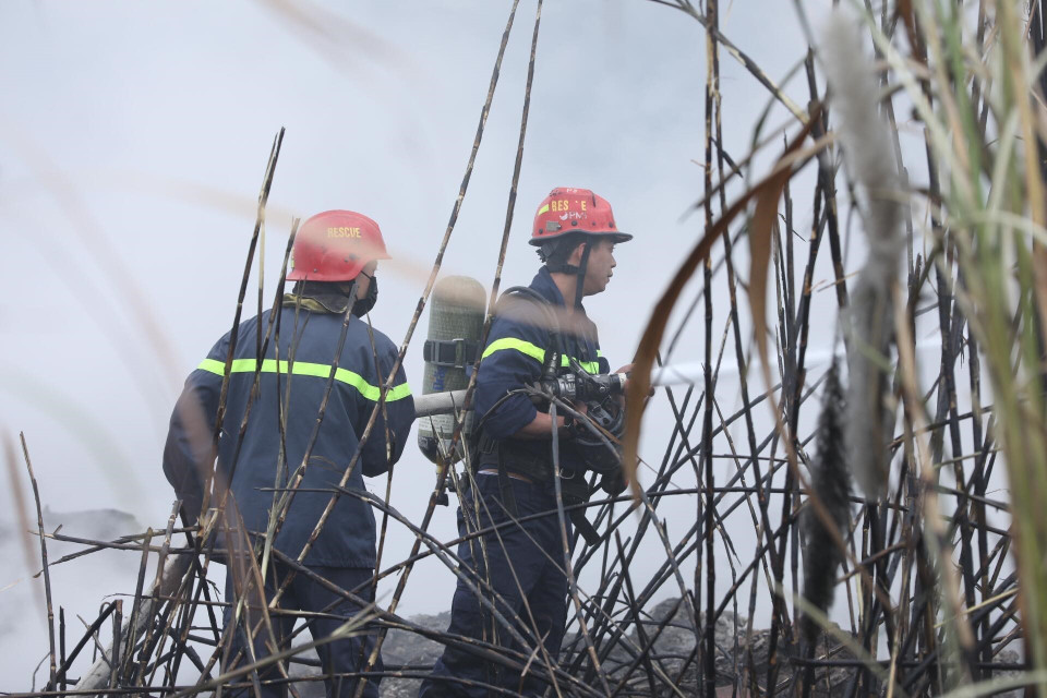 Các chiến sỹ phòng cháy chữa cháy tích cực khống chế ngọn lửa lây lan sang khu vực lân cận. (Ảnh: Thành Đạt/TTXVN)