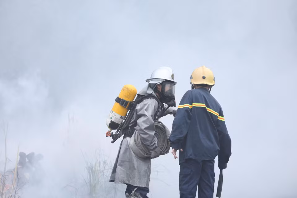 Các chiến sỹ phòng cháy chữa cháy tích cực khống chế ngọn lửa lây lan sang khu vực lân cận. (Ảnh: Thành Đạt/TTXVN)