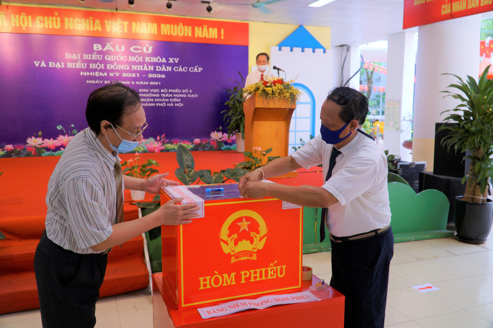 Hai cử tri đại diện lên kiểm tra hòm phiếu và đóng giấy niêm phong. (Ảnh: Minh Hiếu/Vietnam+)