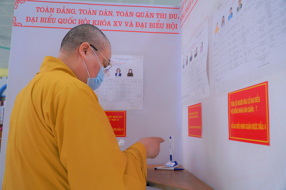 Nhà sư đang kiểm tra phiếu bầu lần cuối trước khi nhét vào hòm. (Ảnh: Minh Hiếu/Vietnam+)