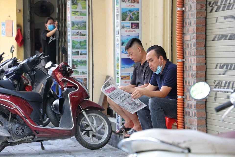 Nhiều người vẫn còn mang tâm lý chủ quan đối với việc phòng chống COVID-19 khi thản nhiên ngồi trên vỉa hè uống trà đá mà không đảm bảo khoảng cách an toàn và không đeo khẩu trang. (Ảnh: Minh Hiếu/Vietnam+)