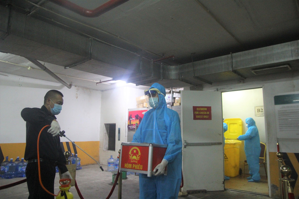 Sau khi hoàn thành mọi công tác tại điểm cách ly, cán bộ tiếp tục phải thực hiện công tác phòng chống dịch trước khi rời khỏi. Hòm phiếu vẫn đảm bảo tuyệt đối về niêm phong trong khâu di chuyển. (Ảnh: PV/Vietnam+)