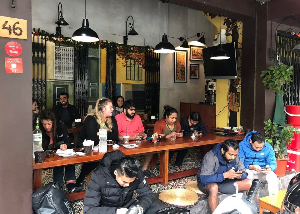 Du khách quốc tế thưởng thức cà phê trên phố Nguyễn Hữu Huân, quận Hoàn Kiếm, trải nghiệm cách sống rất riêng của người Hà Nội: sống trên vỉa hè, ăn cơm trên vỉa hè, nuôi con trên vỉa hè, làm ăn trên vỉa hè. (Ảnh: Minh Quyết/TTXVN)