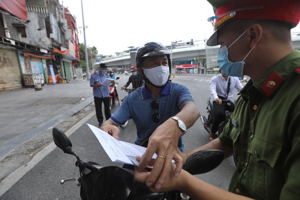 Lực lượng chức năng tại chốt kiểm soát phường Đống Mác (quận Hai Bà Trưng) nhắc nhở người dân cần hoàn thiện các mục còn thiếu đối với giấy đi đường theo quy định mới. (Ảnh: Minh Quyết/TTXVN)