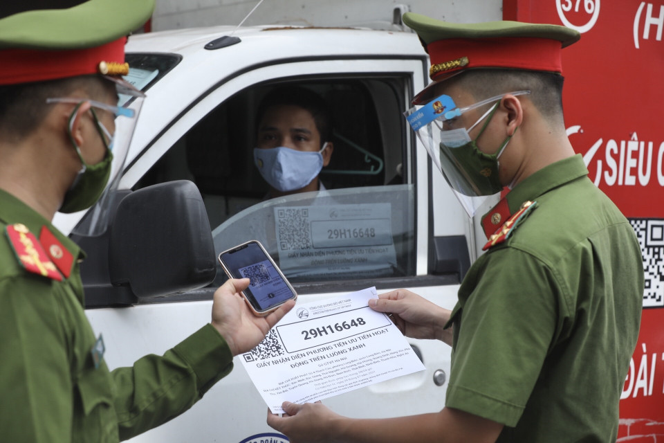 Lực lượng chức năng kiểm tra mã QR Code đối với phương tiện chở hàng thiết yếu. (Ảnh: Minh Quyết/TTXVN)