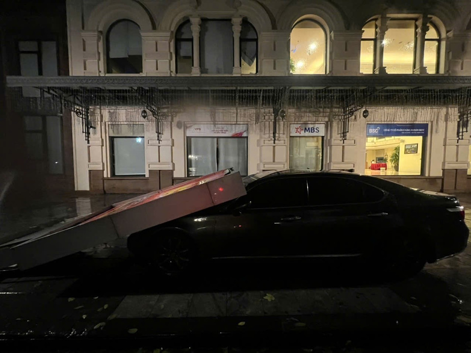 Tấm biển quảng cáo gãy đổ, đè lên xe ô tô trên phố Phan Chu Trinh, quận Hoàn Kiếm (ảnh chụp lúc 22h02). (Ảnh: Phạm Kiên/TTXVN)