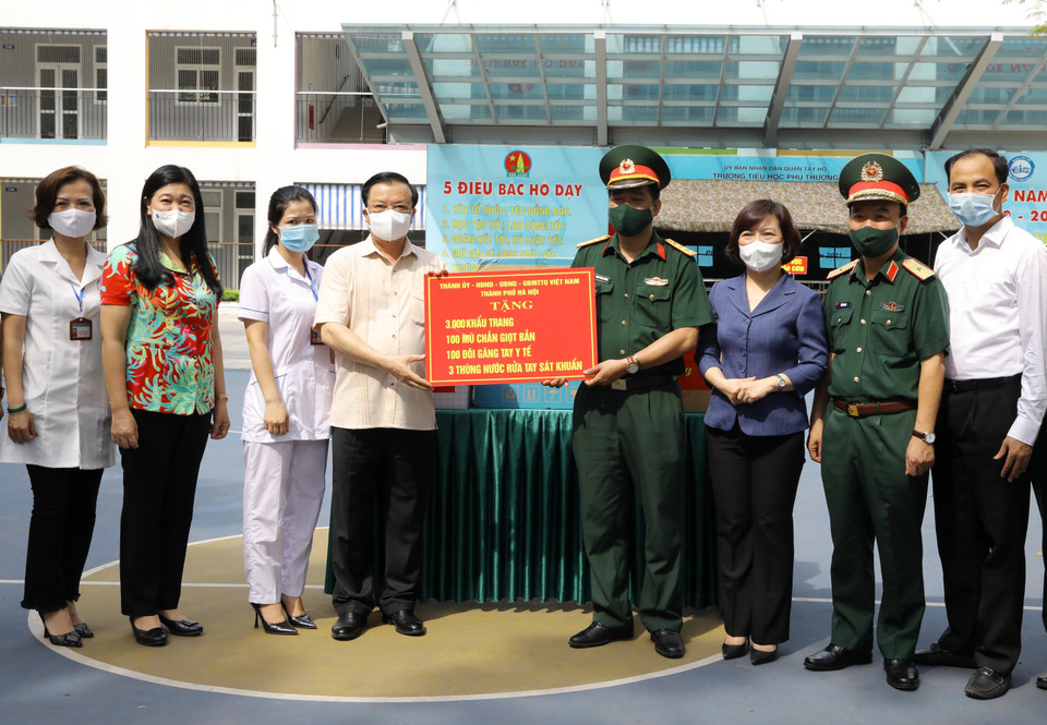 Bí thư Thành ủy Hà Nội Đinh Tiến Dũng trao quà hỗ trợ phòng, chống dịch bệnh COVID-19 tại Khu vực dự phòng cách ly y tế (Trường Tiểu học Phú Thượng, phường Phú Thượng, quận Tây Hồ, Hà Nội). (Ảnh: Nguyễn Điệp/TTXVN)