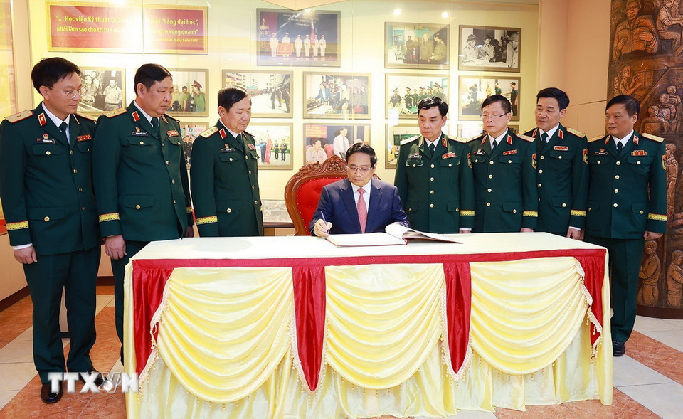 Thủ tướng Phạm Minh Chính viết lưu bút khi đến thăm Học viện Kỹ thuật quân sự. (Ảnh: Dương Giang/TTXVN)