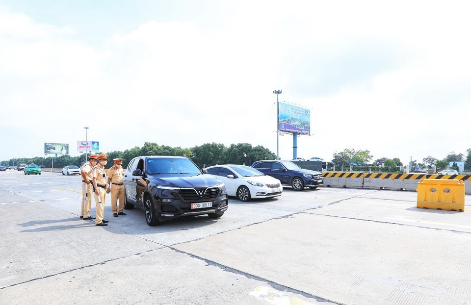 Lực lượng cảnh sát giao thông hướng dẫn các phương tiện đi vào làn thu phí tự động trong ngày đầu tiên thực hiện thí điểm. (Ảnh: Tuấn Anh/TTXVN)