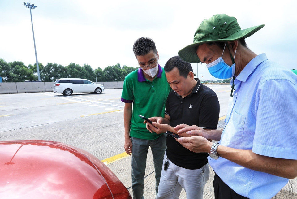 Các nhân viên Công ty Quản lý khai thác đường cao tốc ôtô Hà Nội-Hải Phòng hướng dẫn các lái xe đăng ký tài khoản khi đi qua trạm thu phí tự động. (Ảnh: Tuấn Anh/TTXVN)