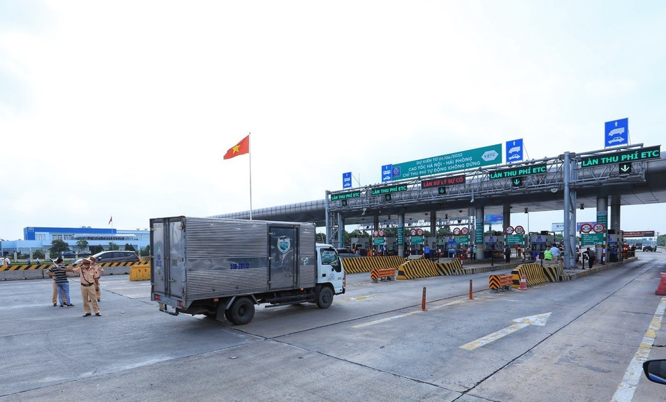 Lực lượng cảnh sát giao thông hướng dẫn các phương tiện đi vào làn thu phí tự động trong ngày đầu tiên thực hiện thí điểm. (Ảnh: Tuấn Anh/TTXVN) 