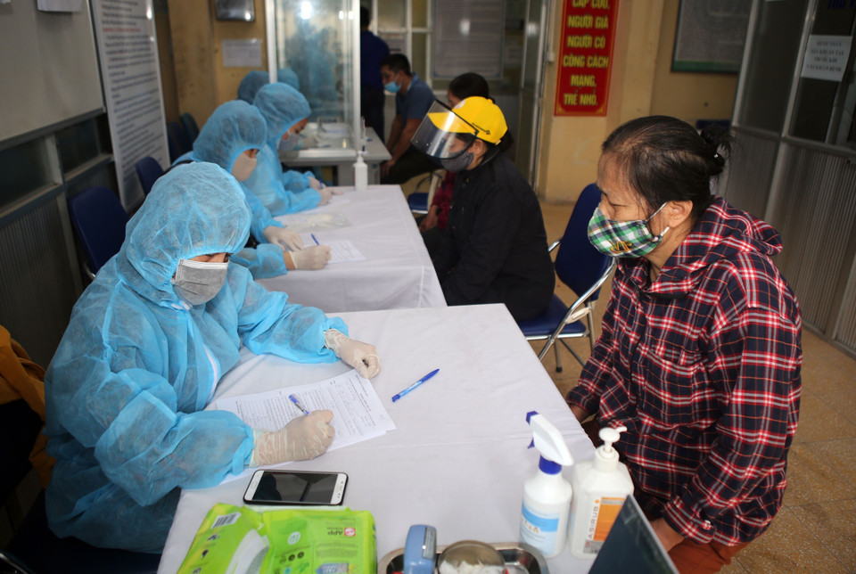 Các tiểu thương chợ đầu mối hoa quả Hoàng Mai làm thủ tục khai báo y tế trước khi lấy mẫu máu xét nghiệm COVID-19, sáng 18/4. (Ảnh: Danh Lam/TTXVN)