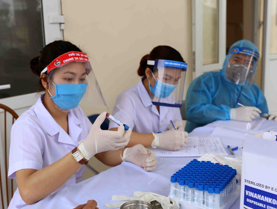 Nhân viêu y tế lấy mẫu máu xét nghiệm nhanh COVID-19 cho người dân xã Lê lợi và các hộ tiểu thương kinh doanh trong chợ đầu mối gia cầm Hà Vĩ (huyện Thường Tín), sáng 18/4. (Ảnh: Vũ Sinh/TTXVN)