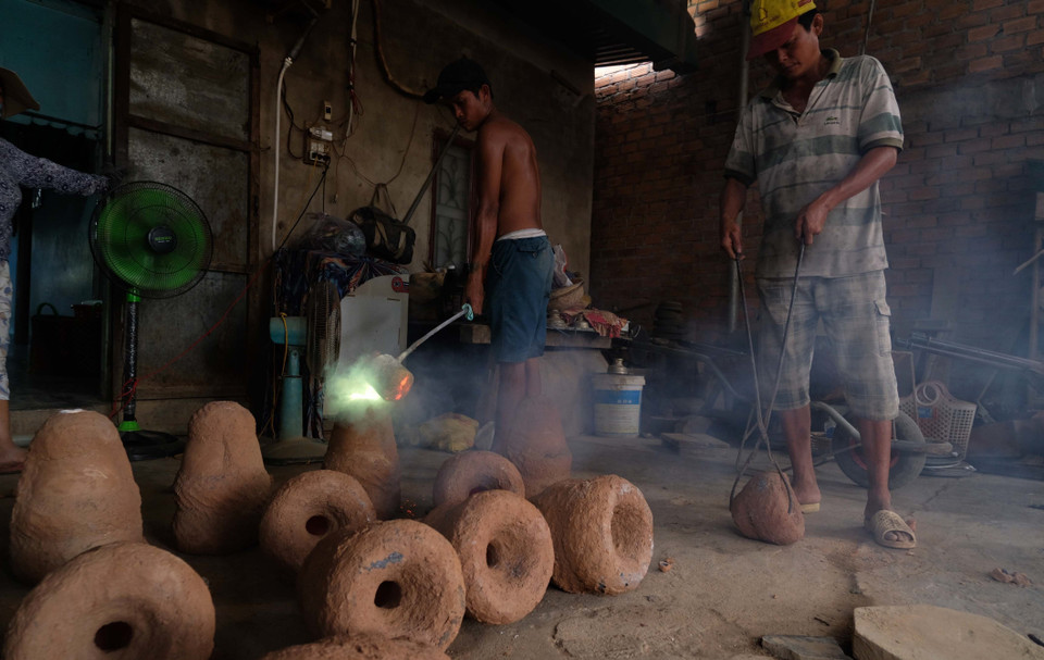 Công nhân tại một cơ sở đổ đồng nung chảy vào các khuôn đất được tạo hình sẵn. (Ảnh: Nguyễn Dũng/TTXVN)