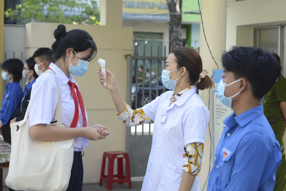 Học sinh được đo thân nhiệt, rửa tay bằng nước sát khuẩn trước khi vào phòng thi. (Ảnh: Văn Dũng/TTXVN)