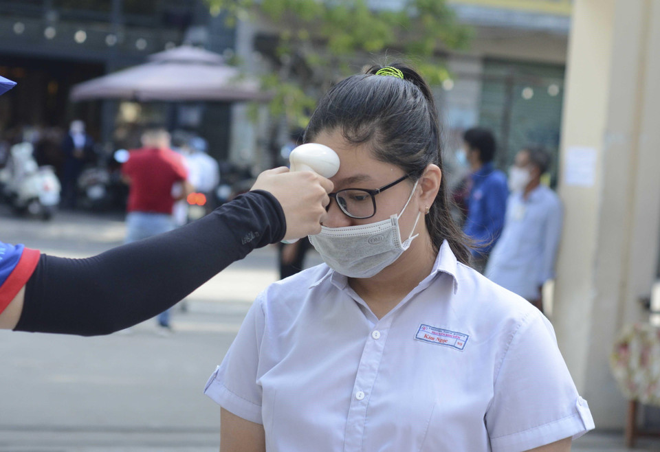 Học sinh được đo thân nhiệt, rửa tay bằng nước sát khuẩn trước khi vào phòng thi. (Ảnh: Văn Dũng/TTXVN)