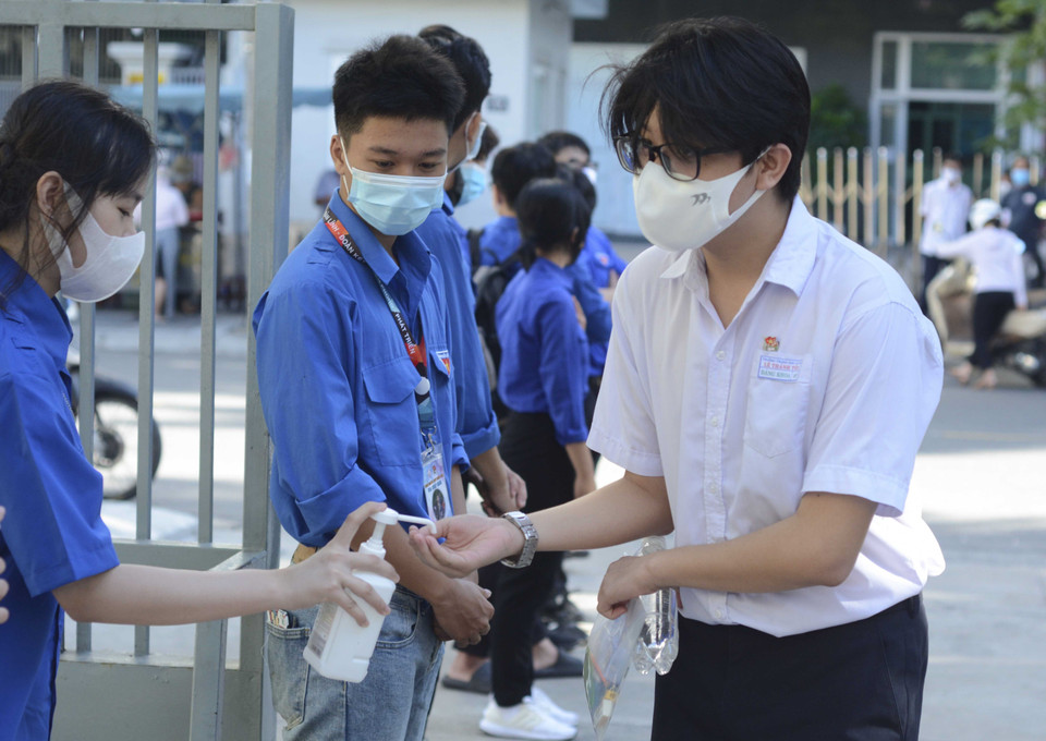 Học sinh được đo thân nhiệt, rửa tay bằng nước sát khuẩn trước khi vào phòng thi. (Ảnh: Văn Dũng/TTXVN)