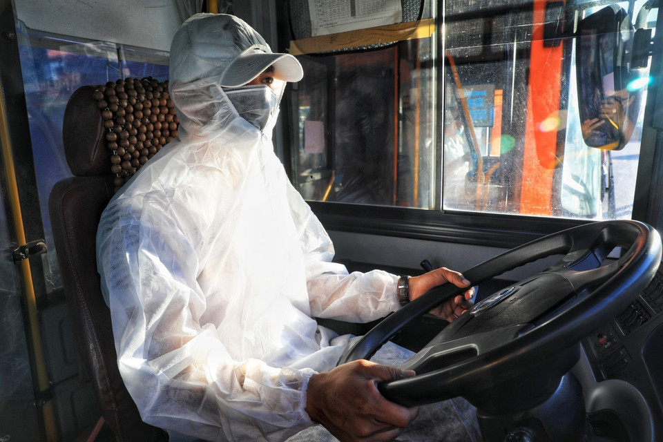 Công nhân lái xe đeo khẩu trang, mặc quần áo bảo hộ phòng, chống dịch theo quy định trước khi lên đường. (Ảnh: Thành Đạt/TTXVN)