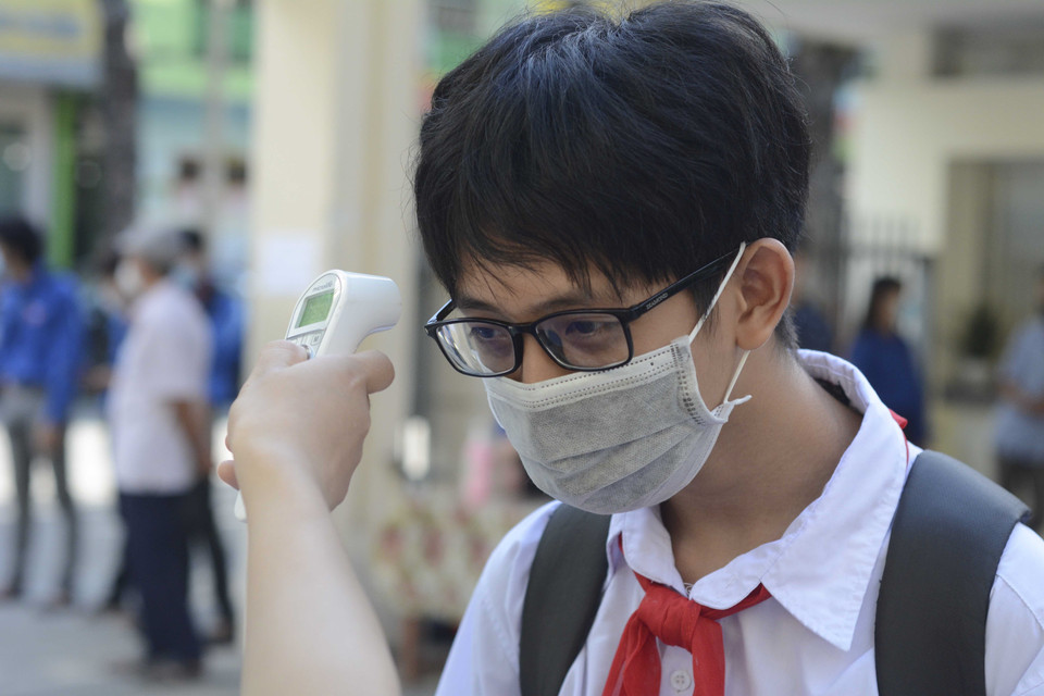 Học sinh được đo thân nhiệt, rửa tay bằng nước sát khuẩn trước khi vào phòng thi. (Ảnh: Văn Dũng/TTXVN)