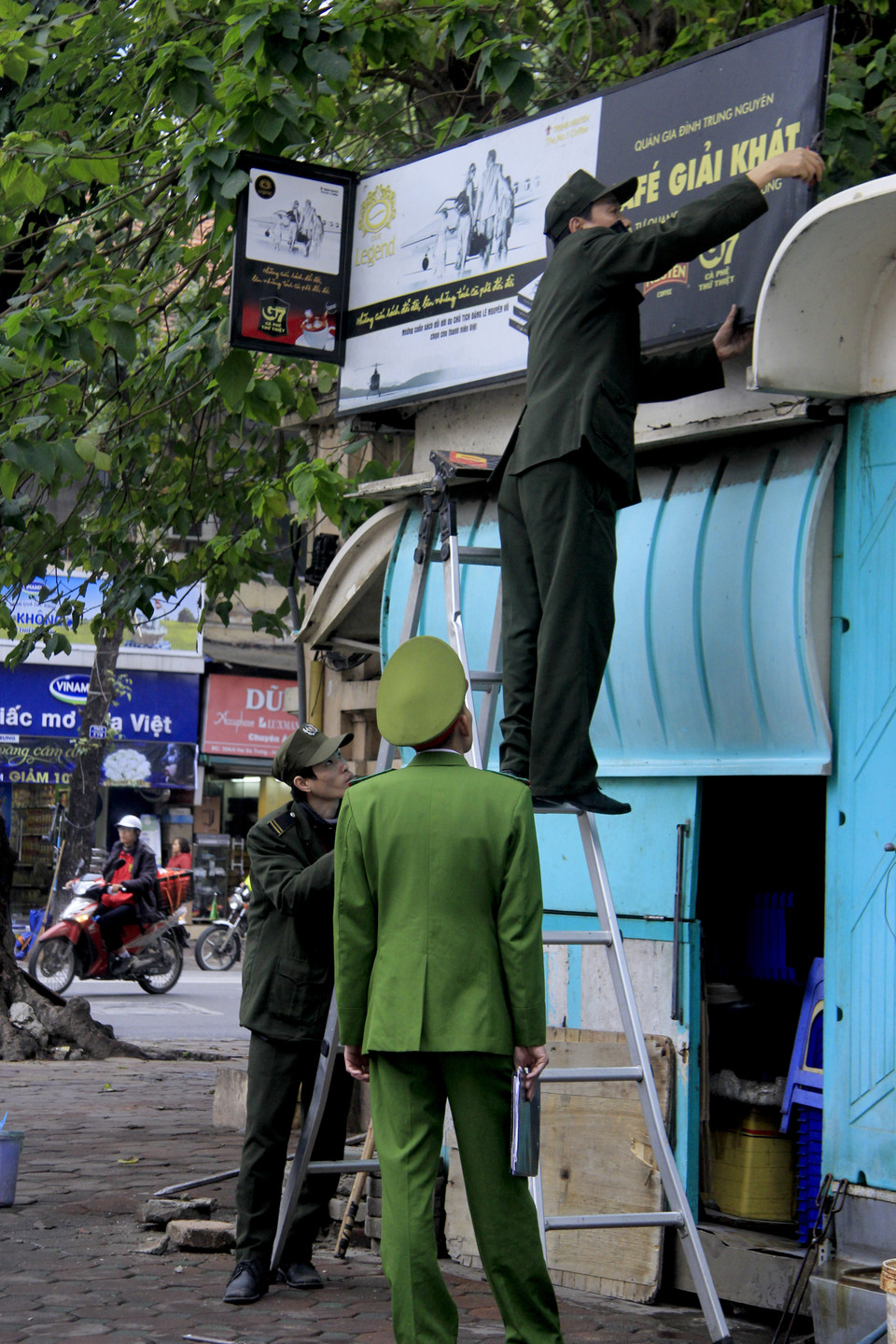 Công an quận Hai Bà Trưng tiến hành tháo dỡ biển quảng cáo. (Ảnh: Thùy Dương/TTXVN)