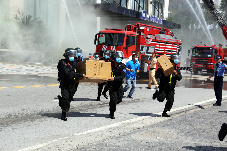 Lực lượng di chuyển hàng hóa, đồ vật ra khỏi khu vực cháy, nổ. (Ảnh: Đức Hiếu/TTXVN)