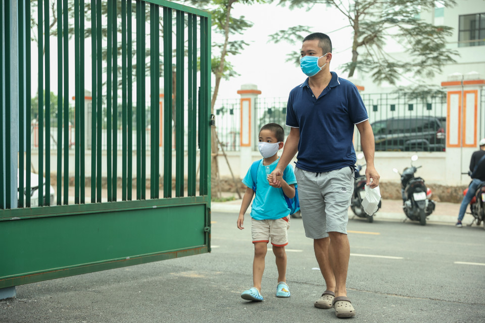Phụ huynh rảo bước dắt con em vào trường. (Ảnh: Minh Hiếu/Vietnam+)