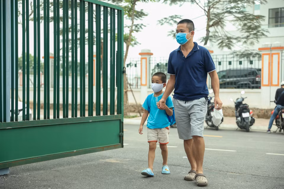 Phụ huynh rảo bước dắt con em vào trường. (Ảnh: Minh Hiếu/Vietnam+)