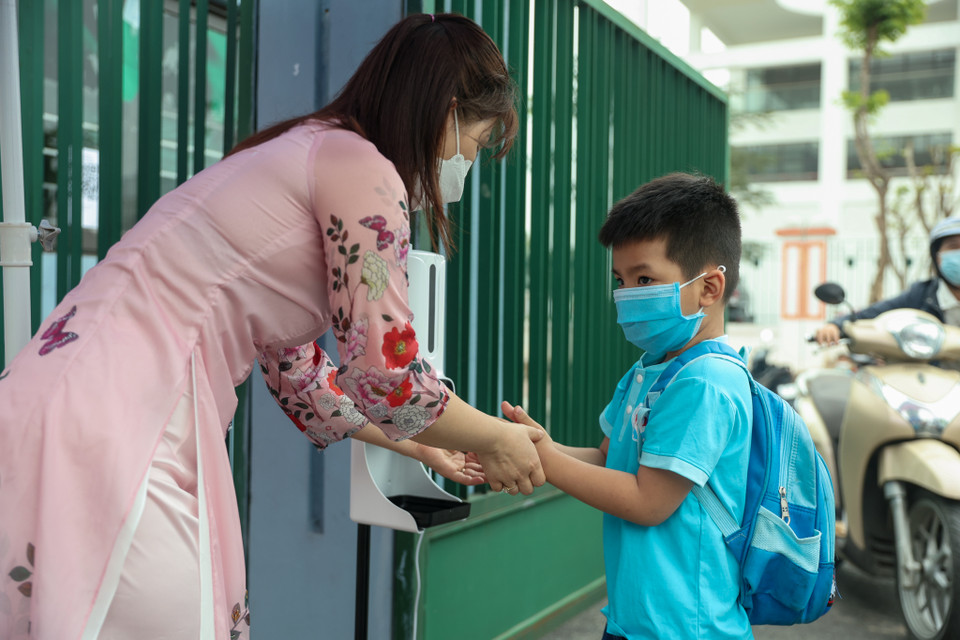 Khi bước vào trường, các em học sinh sẽ được các cô giáo hướng dẫn rửa tay sát khuẩn. (Ảnh: Minh Hiếu/Vietnam+)