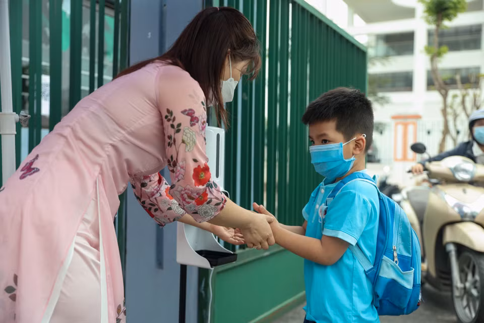 Khi bước vào trường, các em học sinh sẽ được các cô giáo hướng dẫn rửa tay sát khuẩn. (Ảnh: Minh Hiếu/Vietnam+)