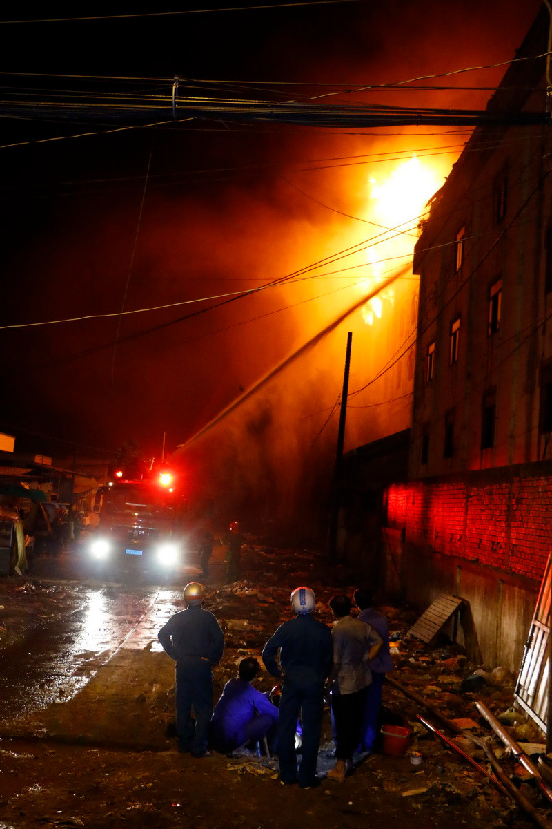 Cảnh sát phòng cháy chữa cháy tập trung khống chế đám cháy bùng phát trở lại tại tòa nhà còn lại. (Ảnh: Thanh Liêm/TTXVN)