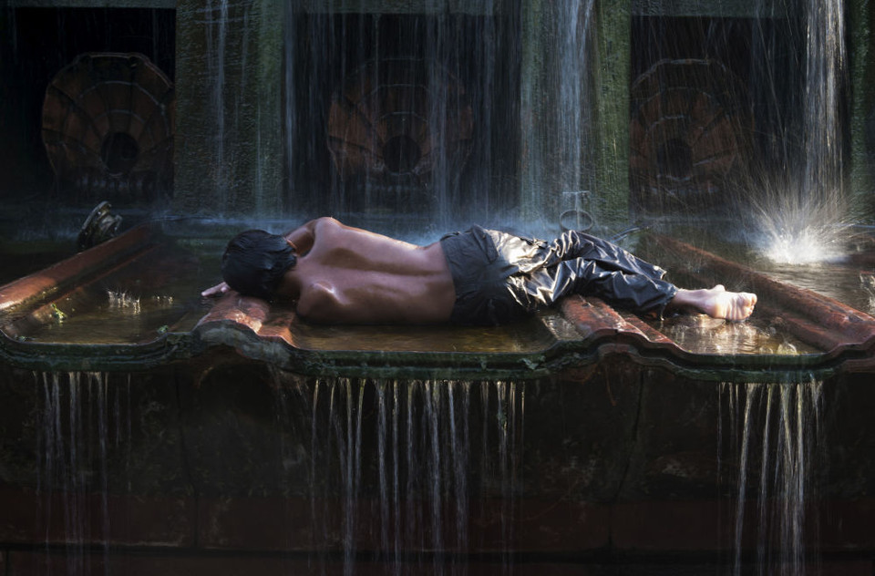 Cậu bé 10 tuổi Golu sống lang thang trên đường phố tại thủ đô New Delhi của Ấn Độ, nằm trên một đài phun nước gần tượng đài India Gate trong một tối hè nóng bức. (Nguồn: Sputnik)