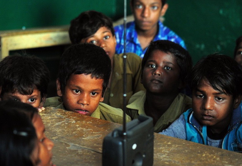 Những học sinh vây quanh một chiếc đài, chăm chú nghe Thủ tướng Ấn Độ Narendra Modi phát biểu nhân dịp ngày Nhà giáo tại một trường tiểu học ở thành phố Bakshi Kala Daraganj. Modi đã gửi bài diễn thuyết của mình tới hàng trăm ngàn học sinh trên khắp Ấn Độ thông qua chương trình trực tiếp.