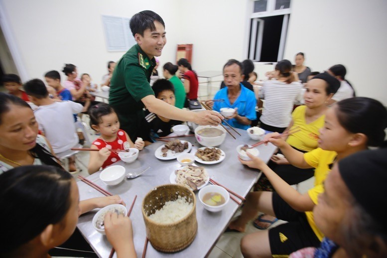 Cán bộ, chiến sỹ Đồn biên phòng Tam Chung ân cần chăm lo bữa ăn tối của người dân Bản Poọng đang tạm trú tại đơn vị. (Ảnh: Quyết Đạt/TTXVN)