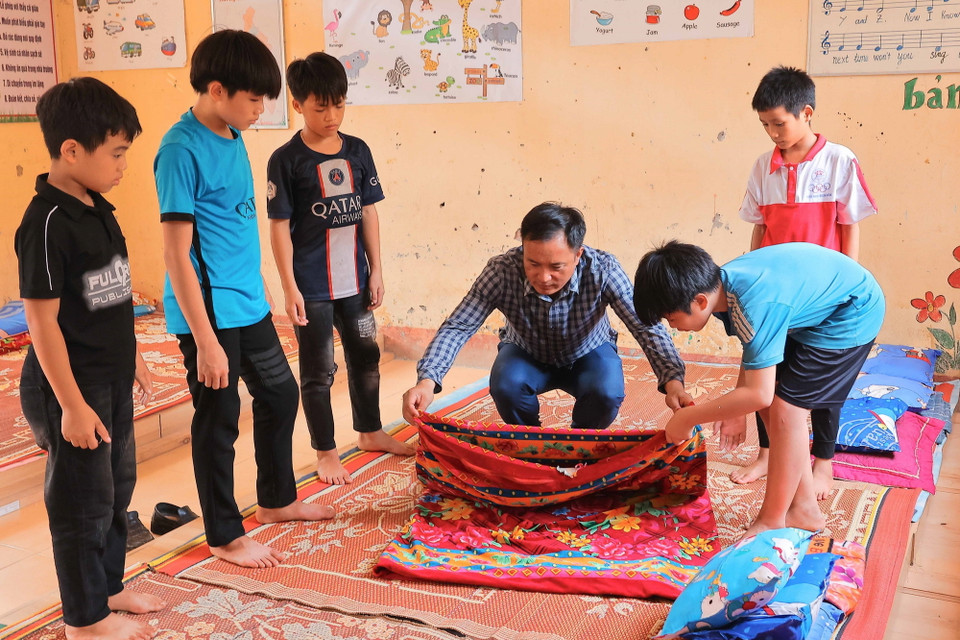 Thầy hiệu trưởng Phạm Đức Vinh tận tình hướng dẫn học sinh thôn Làng Nủ tại nơi ở mới. (Ảnh: Hoàng Hiếu/TTXVN)