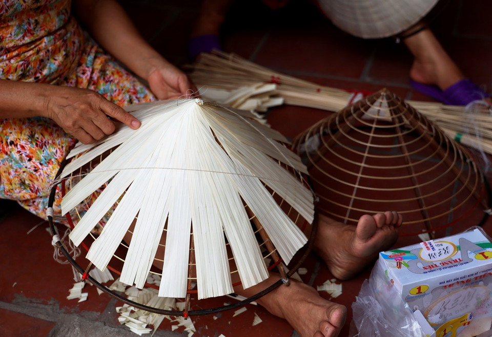 Quay nón (đưa lá lên khung cho đều trước khi may), một công đoạn quan trọng để làm ra một chiếc nón lá. (Ảnh: Hồng Đạt/TTXVN)