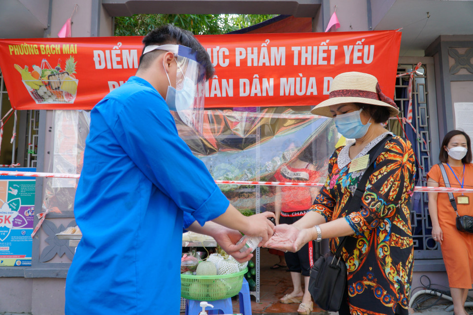 Người đến mua hàng đều chấp hành nghiêm túc thực hiện 5K của Bộ Y tế. Trước khi vào mua lương thực, thực phẩm, người dân bắt buộc phải đo nhiệt độ, rửa tay sát khuẩn, đeo khẩu trang. (Ảnh: Minh Hiếu/Vietnam+)