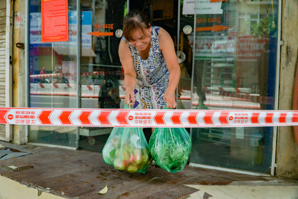 Người dân tại điểm cách ly phố Lê Thanh Nghị (quận Hai Bà Trưng) vui mừng khi nhận được thực phẩm từ lực lượng 'đi chợ hộ.' (Ảnh: Minh Hiếu/Vietnam+)