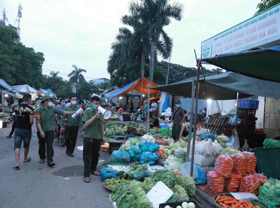 Lực lượng chức năng chợ đầu mối Minh Khai dùng loa tuyên truyền, nhắc nhở người dân thực hiện nghiêm các quy định về phòng chống dịch. (Ảnh: Vũ Sinh/TTXVN)